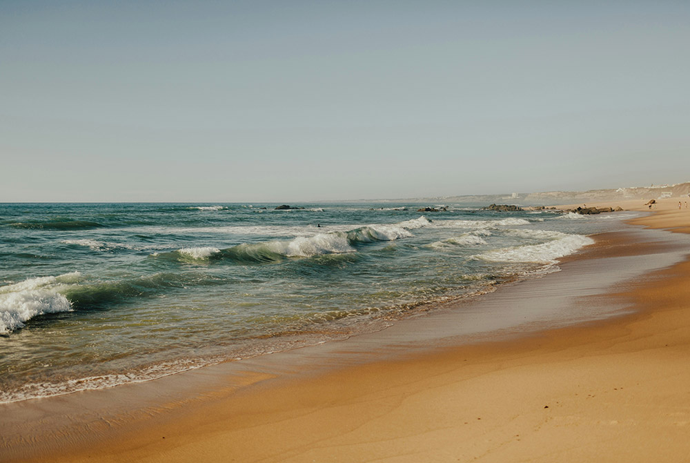 View of a beach with waves rolling into the shore.