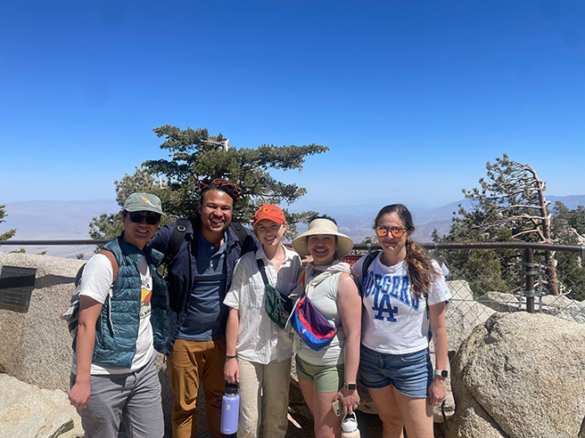 A group of people stand in front of a scenic overlook.