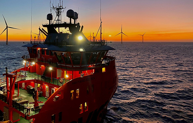 A construction boat near wind turbines in the ocean.