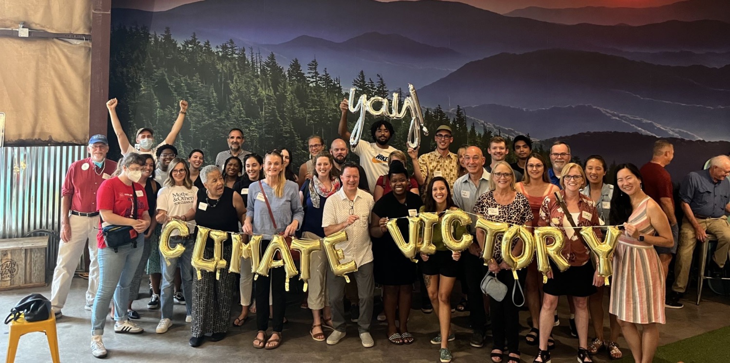 Group posing with gold balloons spelling "Climate Victory"