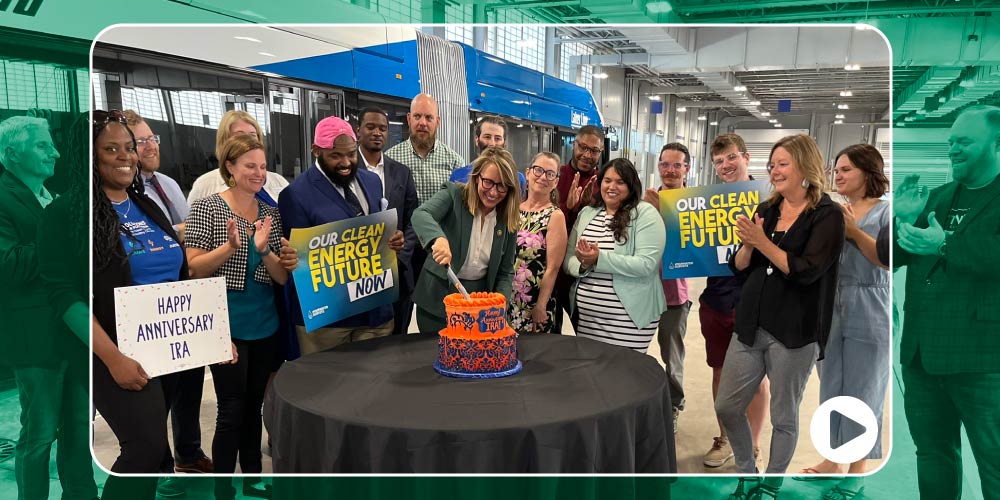 A video thumbnail of a group celebrating one year of the Inflation Reduction Act with a cake