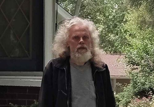 Kenneth stands outside his home.