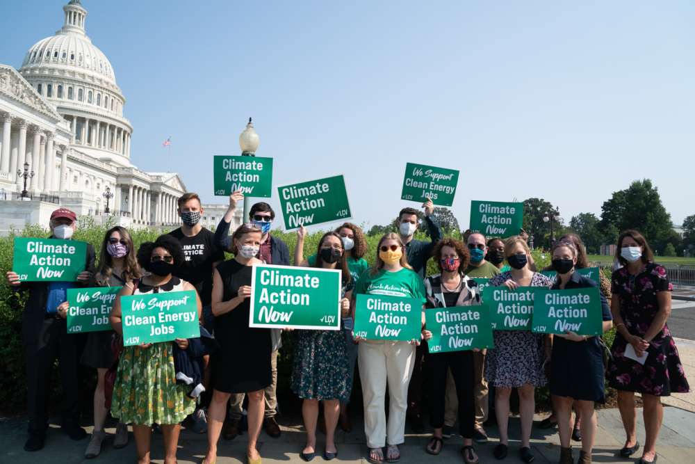 LCV staff hold signs that read "Climate Action Now" and "We Support Clean Energy Jobs" in front of Capitol building in D.C.