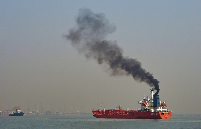 A ship in the port of Mumbai emitting black pollution smoke.