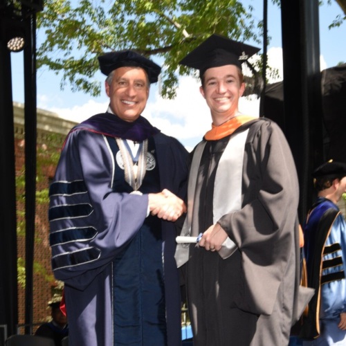 Max in graduation gown with professor