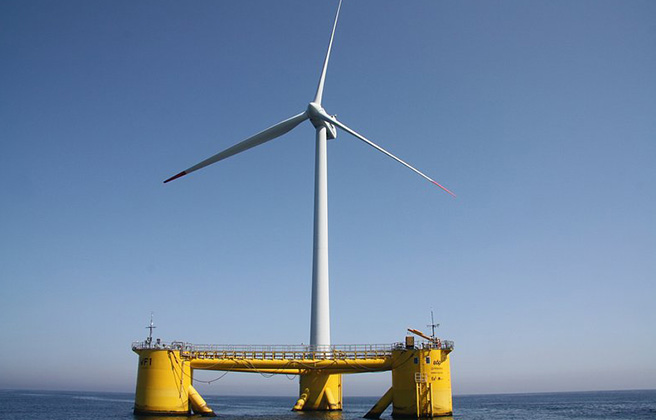 A yellow platform next to white offshore wind turbines.