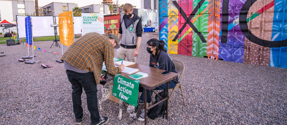 Person signing a petition in front of an art exhibit.