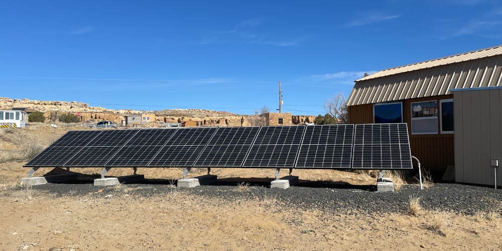 A solar panel next to a house on desert land