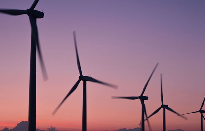 Wind turbines spinning as the sun sets.